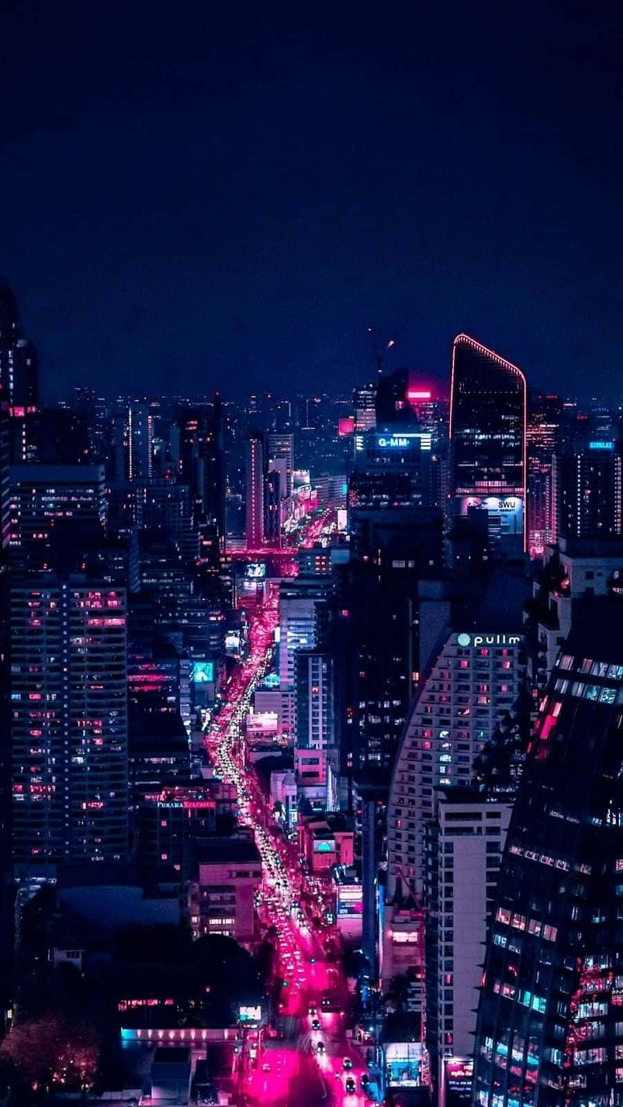 逃離平凡，探索霓虹都市 壁紙 — 夜晚充滿活力的霓虹燈城市景觀，高聳的摩天大樓和下方發光的粉紅色街道。