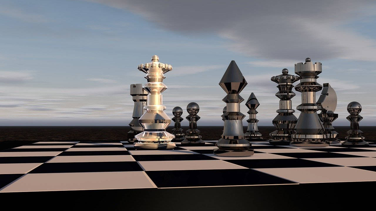 透明棋盤風景 壁紙 — 巨大的金屬國際象棋棋子矗立在廣闊的棋盤上，背景是無盡水域上方的多雲天空。