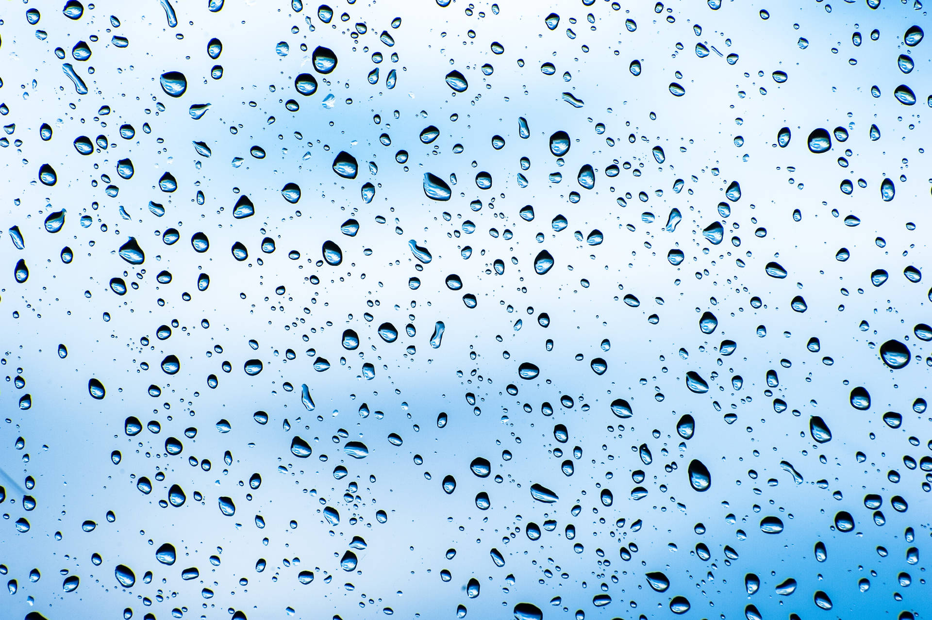 玻璃上的雨滴，透過水滴可見藍天。