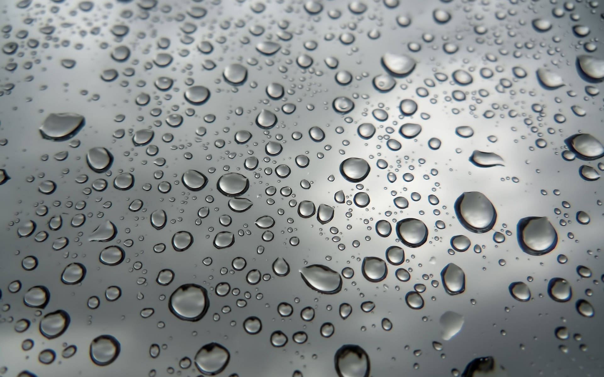 玻璃上的雨滴，背景為模糊的灰色天空