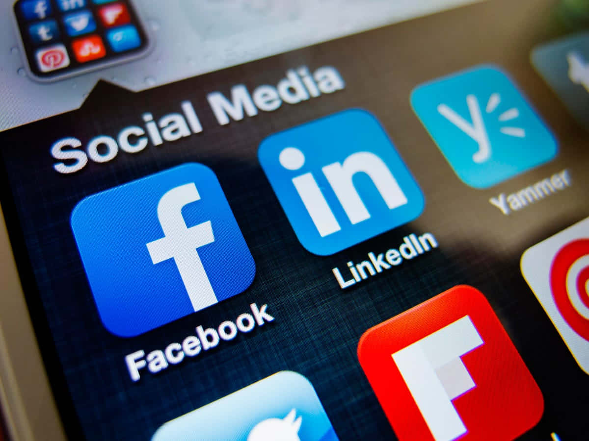 透過 LinkedIn 讓你的職涯夢想成真 壁紙 — 智能手機屏幕特寫，顯示社交媒體應用程式圖示，如 Facebook、LinkedIn 和 Yammer，位於名為「Social Media」的資料夾中。