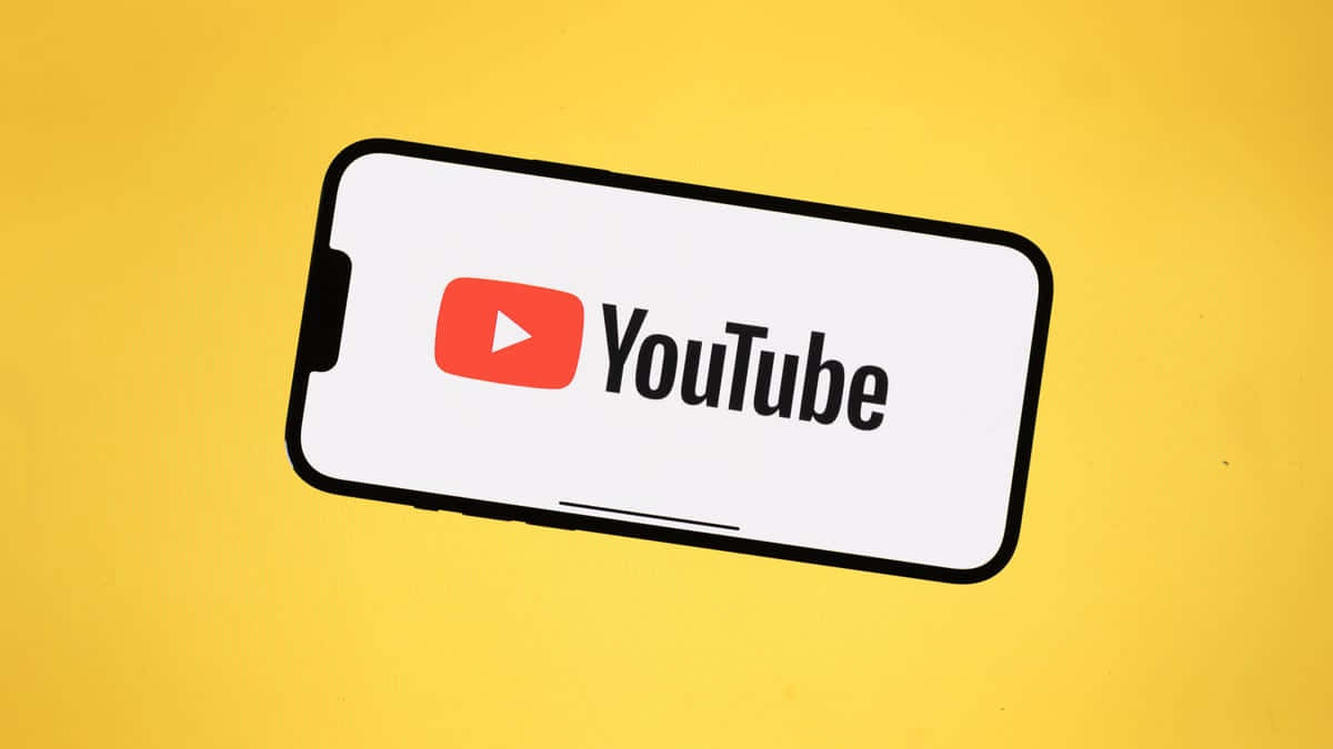 透過 YouTube 自我表達，你的創意與表達平台 壁紙 — 一部智能手機在鮮黃色背景上顯示 YouTube 標誌。