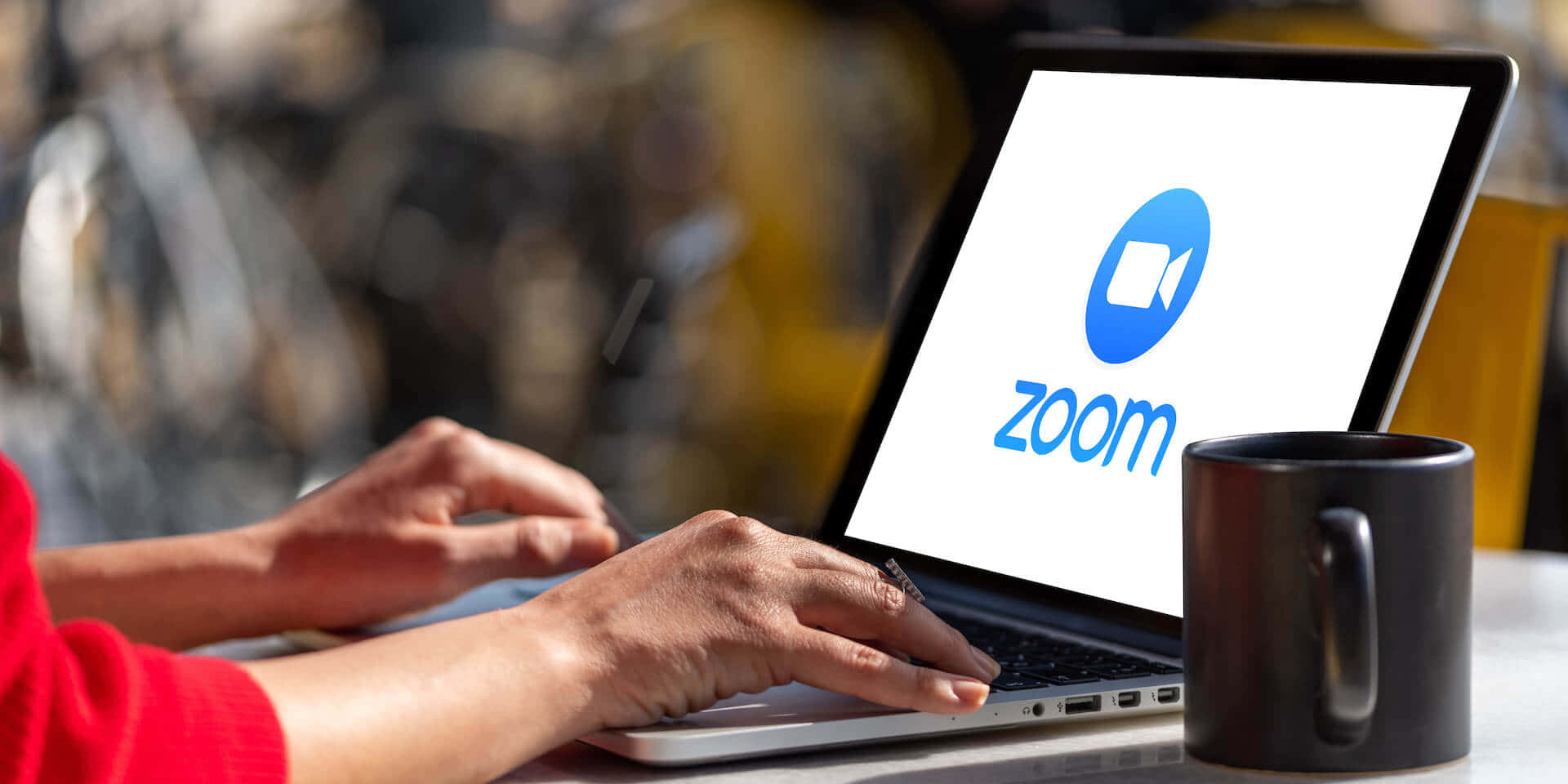 人在戶外用Zoom筆記型電腦遠端工作，旁邊有咖啡杯。