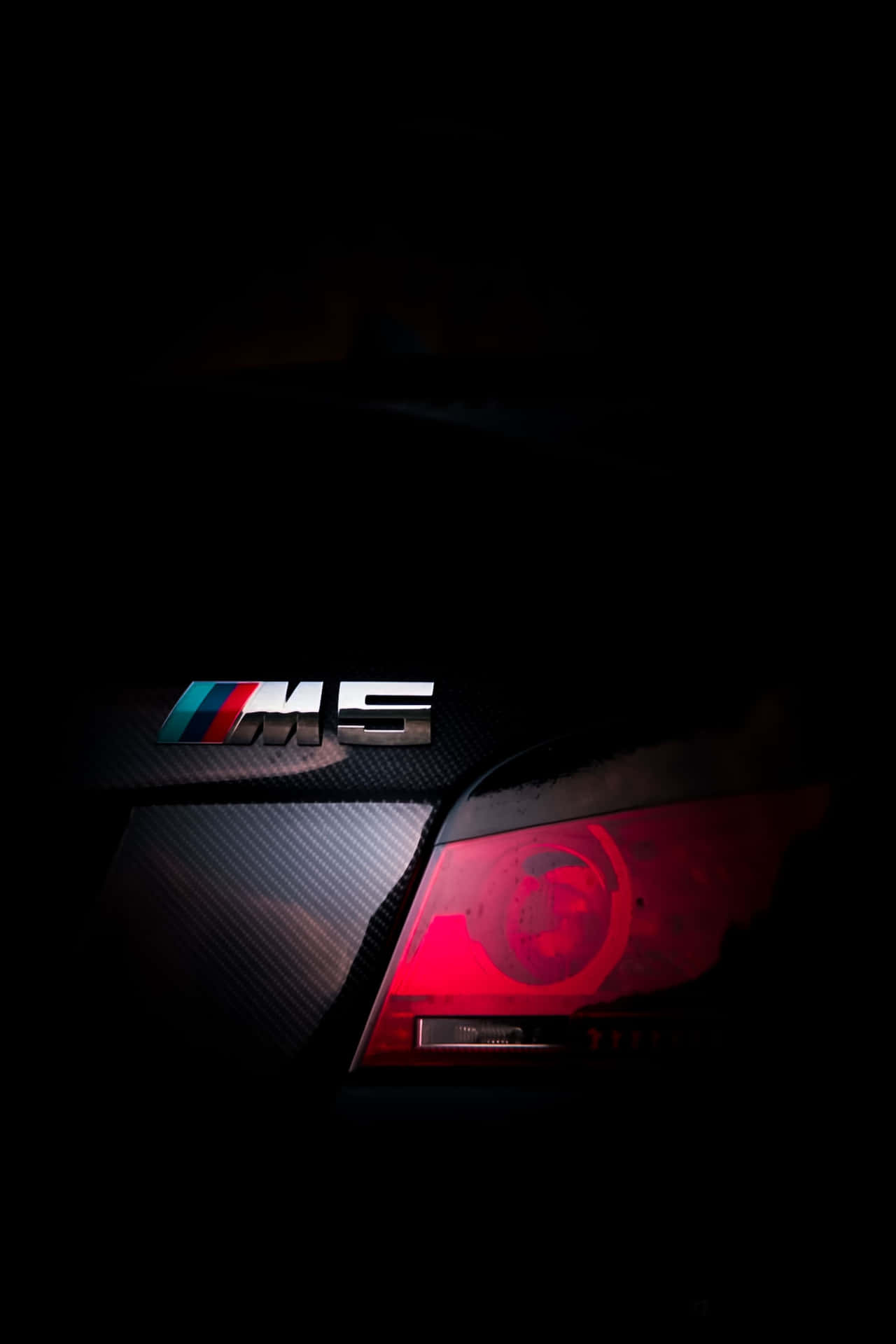 黑暗中發光的BMW M5徽章和紅色尾燈