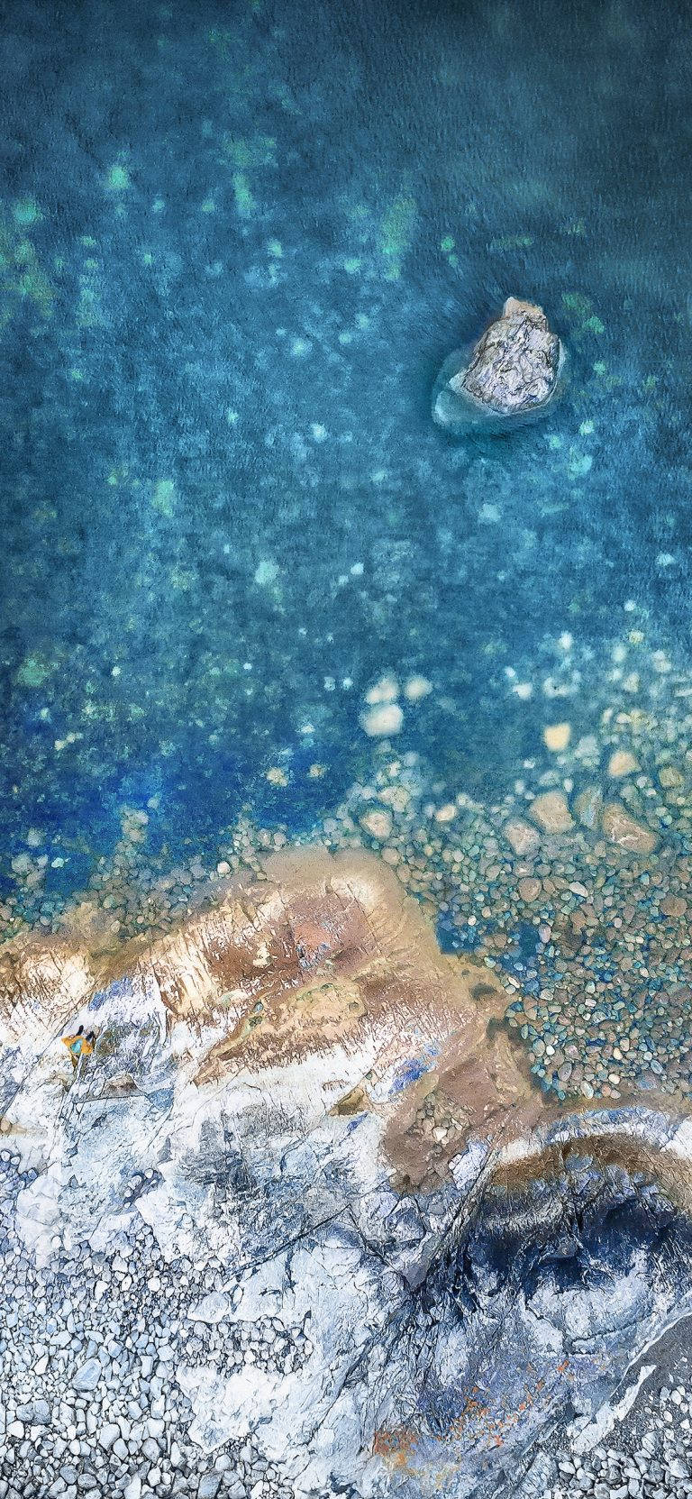 靠近紋理海岸的碧綠海水與岩石和巨石的空中拍攝。
