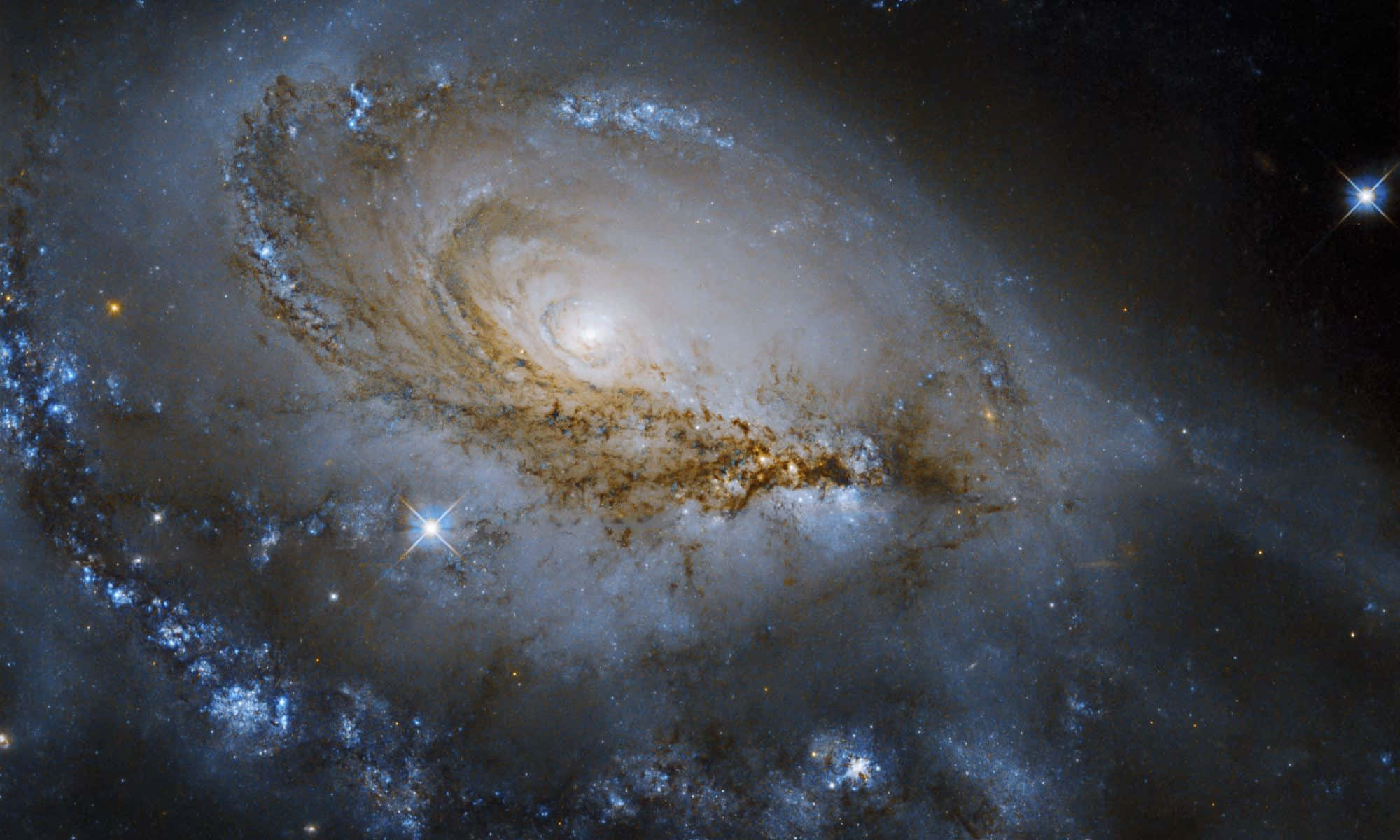 透過哈勃望遠鏡窺探宇宙深處 壁紙 — 一個雄偉的螺旋星系，其發光的藍色和金色塵埃臂在佈滿星辰的宇宙虛空中旋轉。