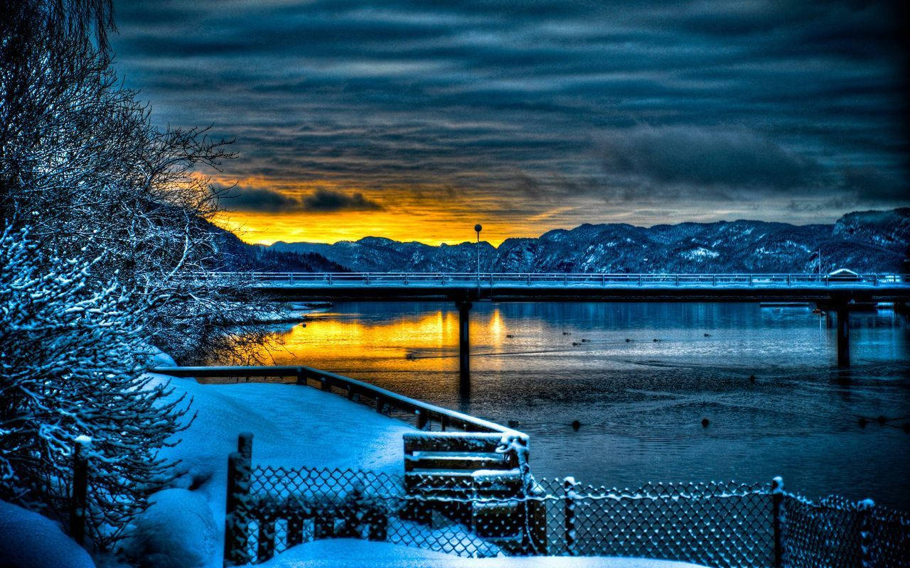 夕陽下湖上的雪橋，橙色天空倒影和霜凍樹木
