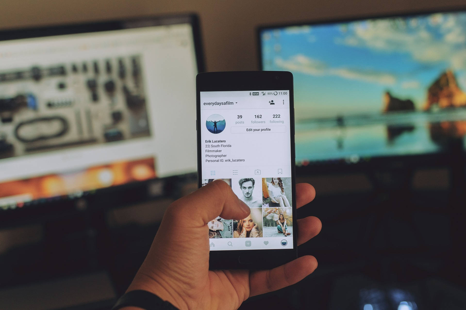 手拿著顯示Instagram個人資料的電話，背後有模糊的電腦屏幕。