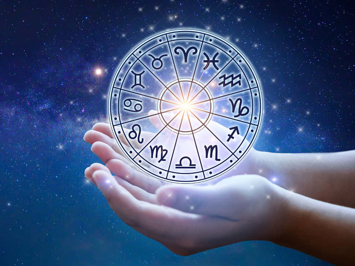 透過星座尋找你的完美配對 壁紙 — 雙手捧著一個發光的星座輪盤，背景是星光燦爛的宇宙，光芒從輪盤中心四射。
