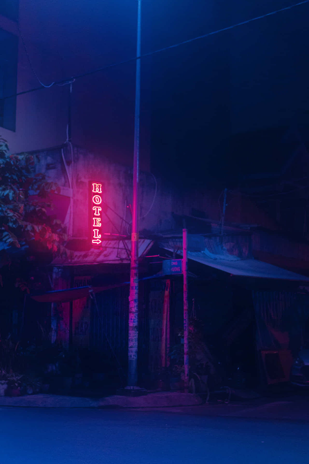 霓虹燈酒店招牌在夜晚用粉紅色和藍色光芒照亮黑暗的城市小巷。