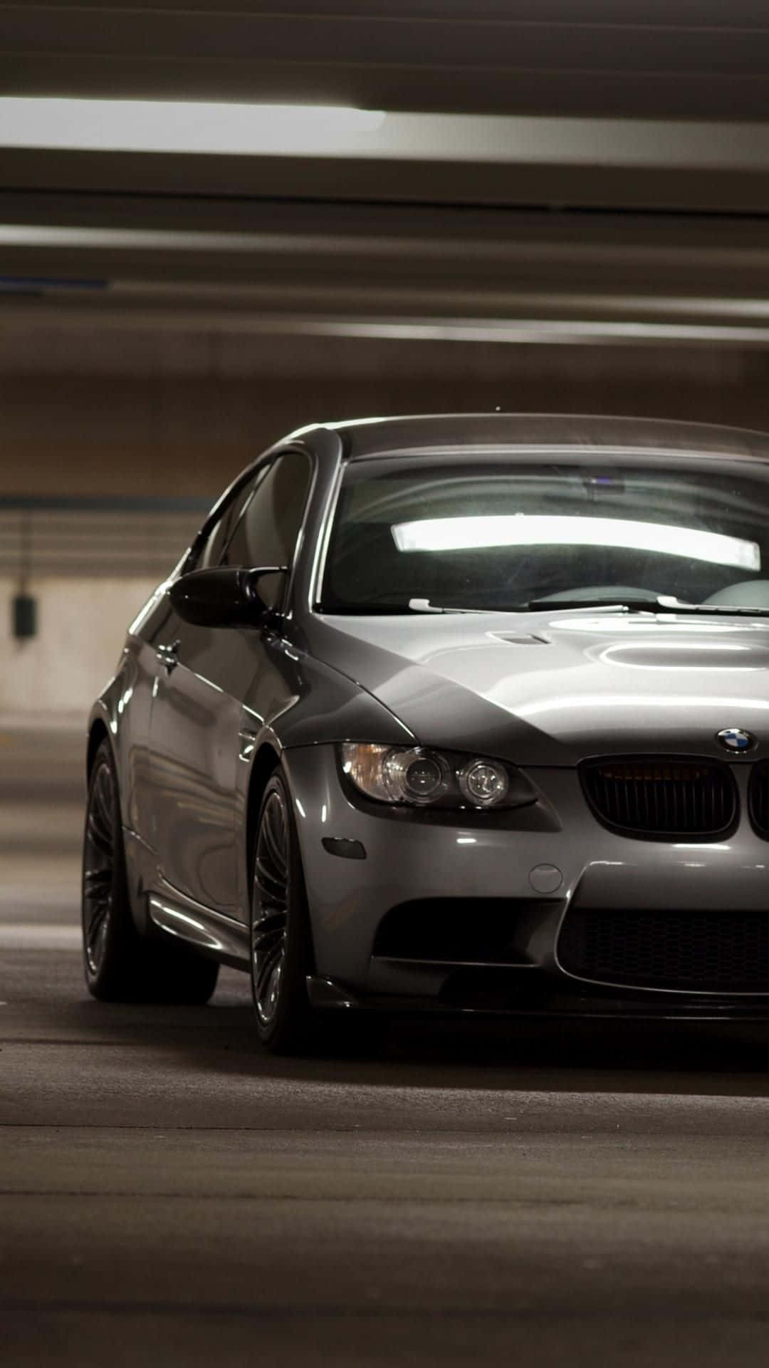 銀色BMW M3轎跑車停泊在地下停車場，上方燈光模糊。