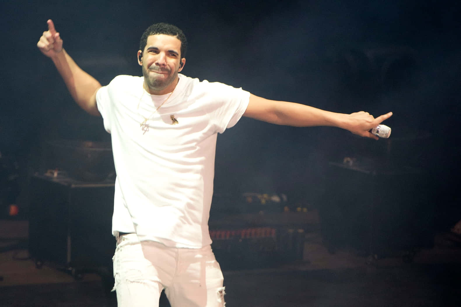 Drake 在演唱會上身穿白色服裝，雙臂伸展，在舞台上微笑。