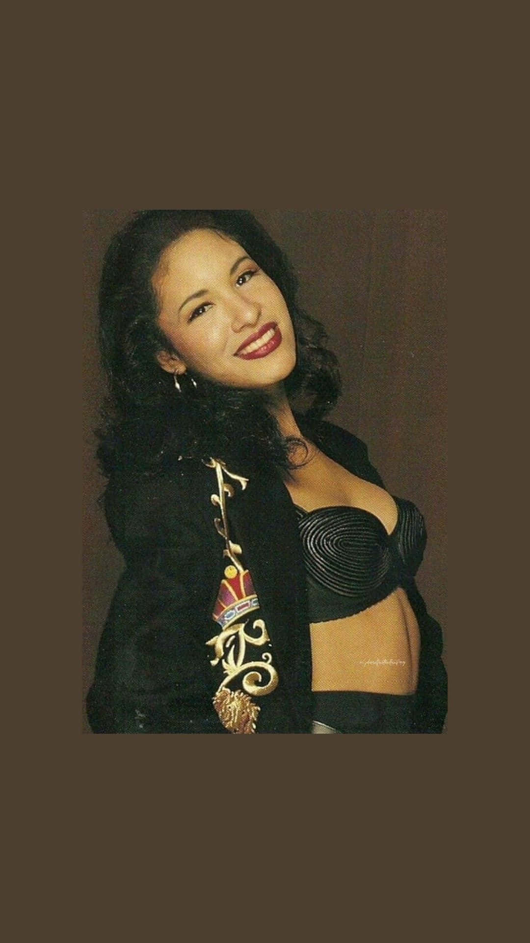 一位微笑的女性，身穿黑色束腰和刺繡外套，為肖像照擺姿勢。