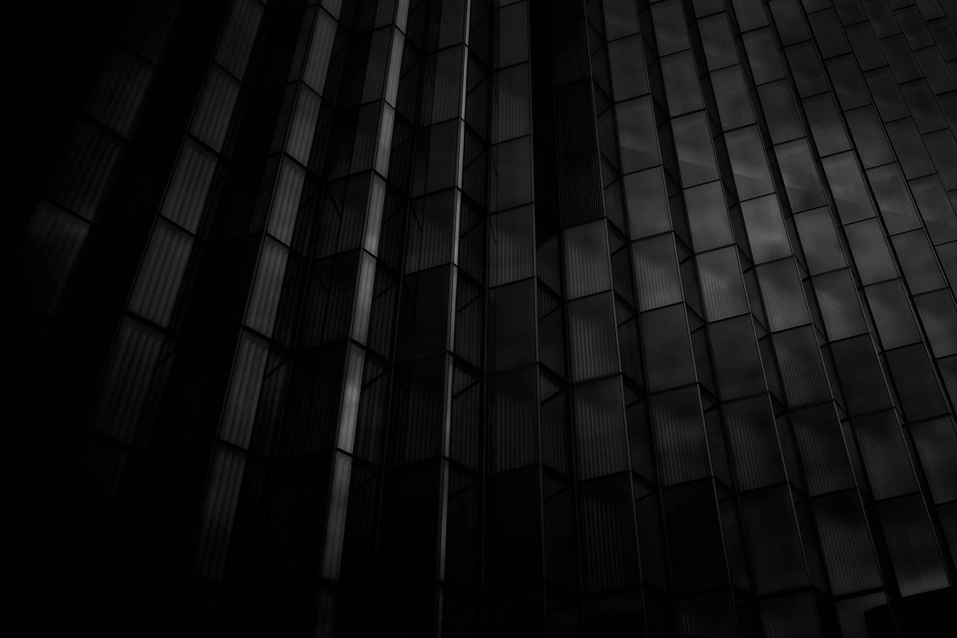 現代建築外牆上深色玻璃面板的抽象建築圖案。