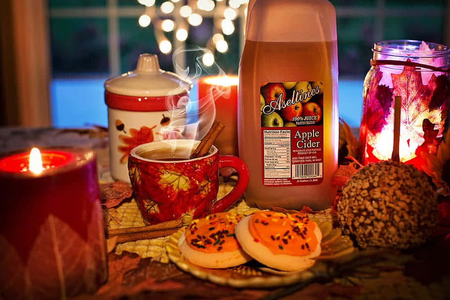 舒適的秋日餐桌，有蘋果酒、蠟燭和蜜餞蘋果。