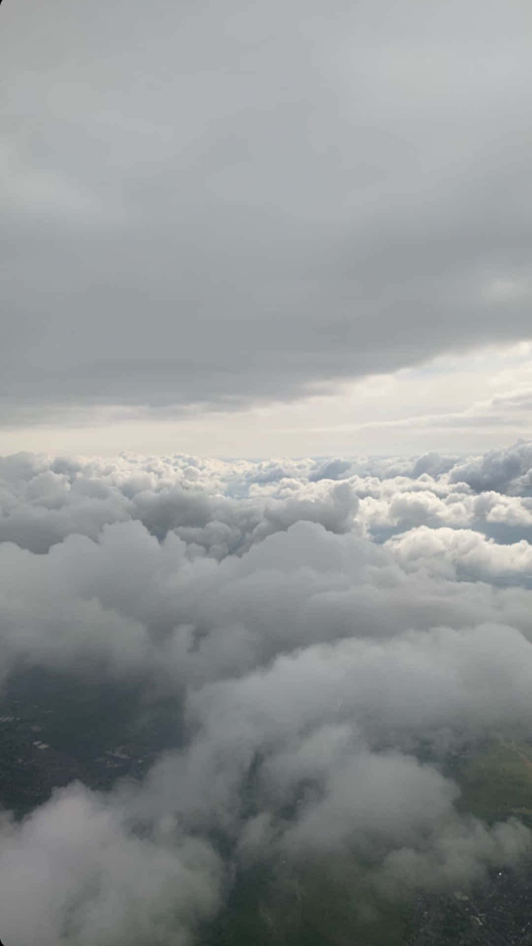 從上方穿過雲層俯瞰下方的綠色景觀。