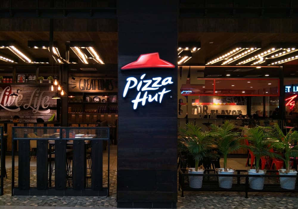 夜晚的Pizza Hut餐廳入口，帶有發光標誌和盆栽植物。