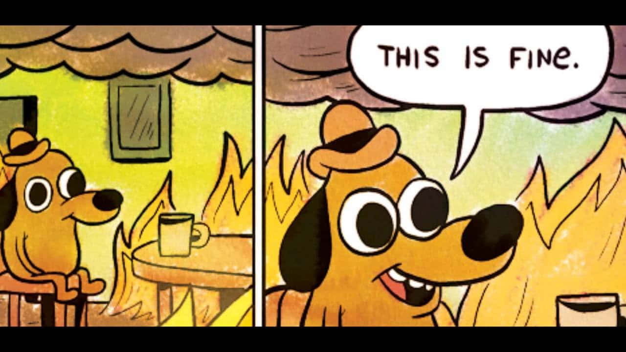 一隻卡通狗在燃燒的房間裡微笑，拿著杯子說「this is fine」。