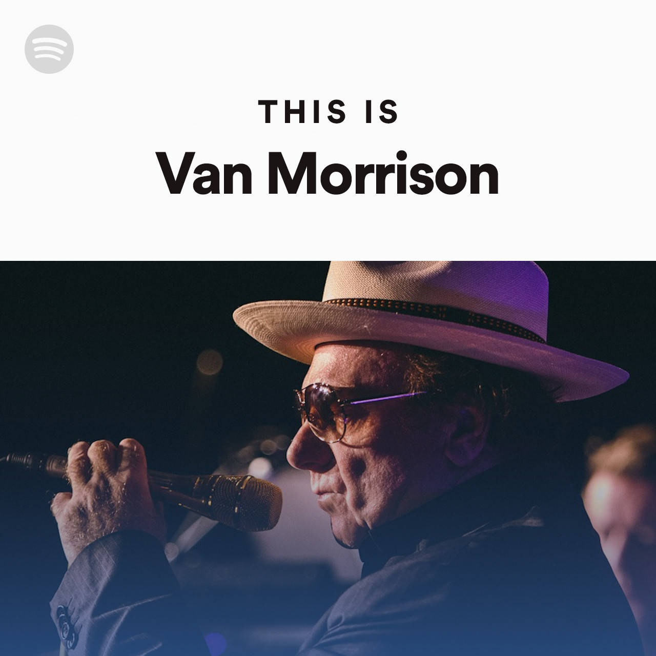 Van Morrison 在舞台上戴著帽子和太陽眼鏡對著麥克風唱歌。