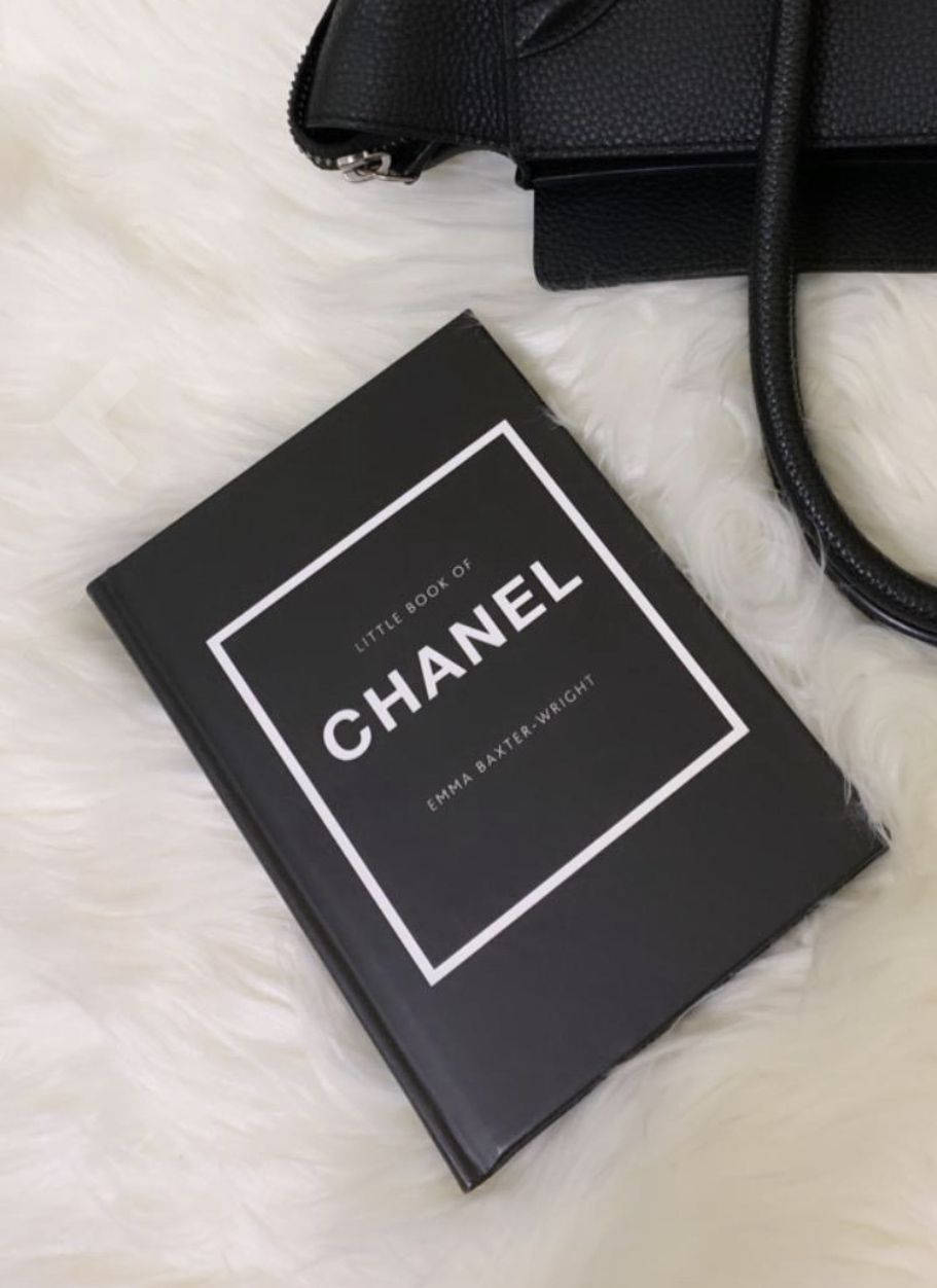 黑色 Chanel 書本和手袋在白色毛絨表面上。