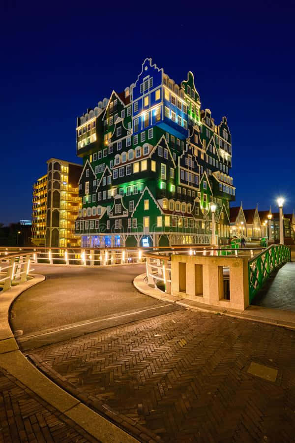 夜晚一座燈火通明的綠色和白色建築，有一座橋樑和鵝卵石小路。