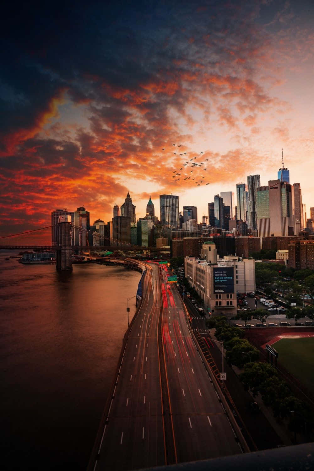 通往城市之路，暮色天空 壁紙 — 紐約市天際線的壯觀日落，高速公路和河流上方有火紅色的雲彩。