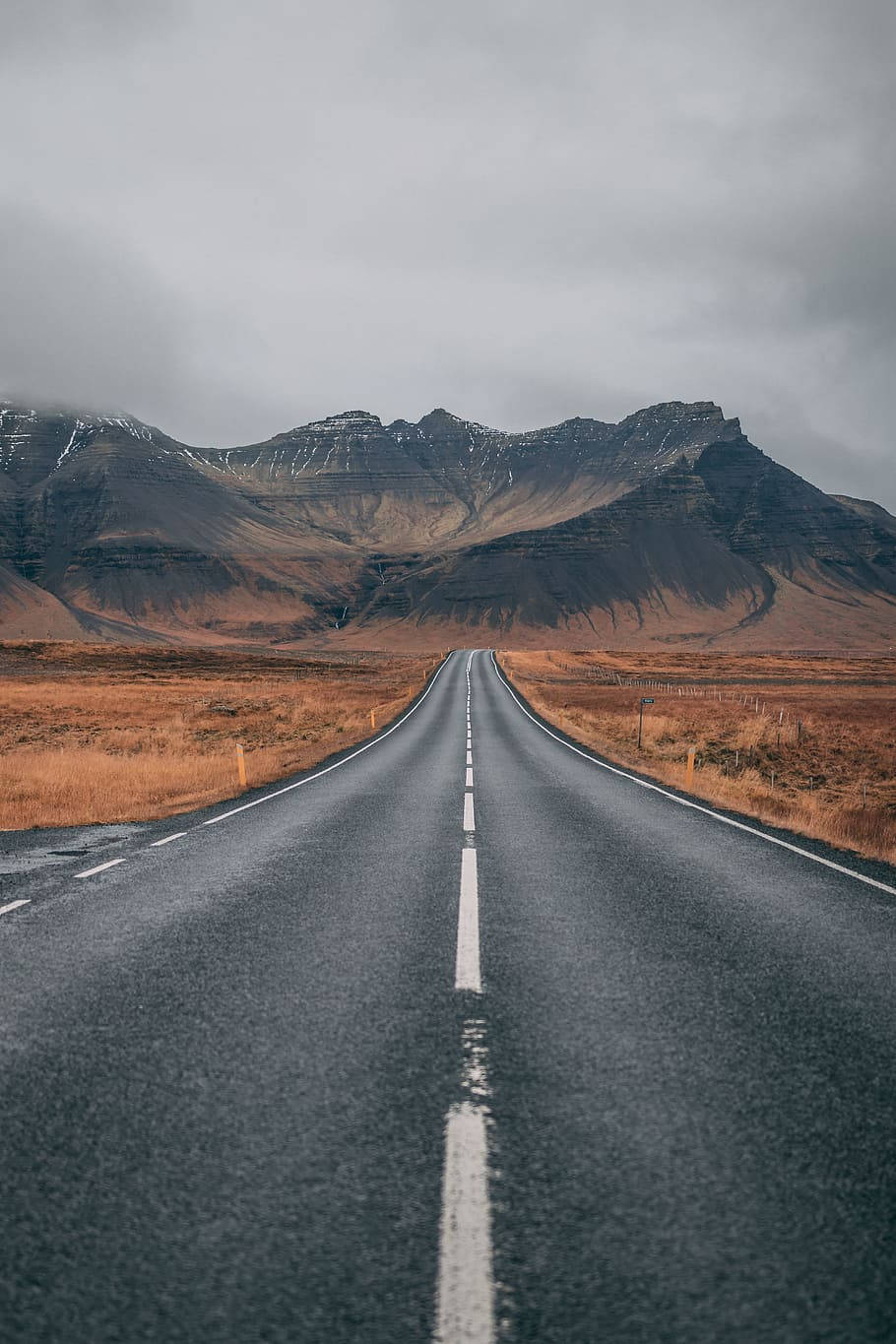 一條空蕩的道路在多雲的天空下通往山脈。
