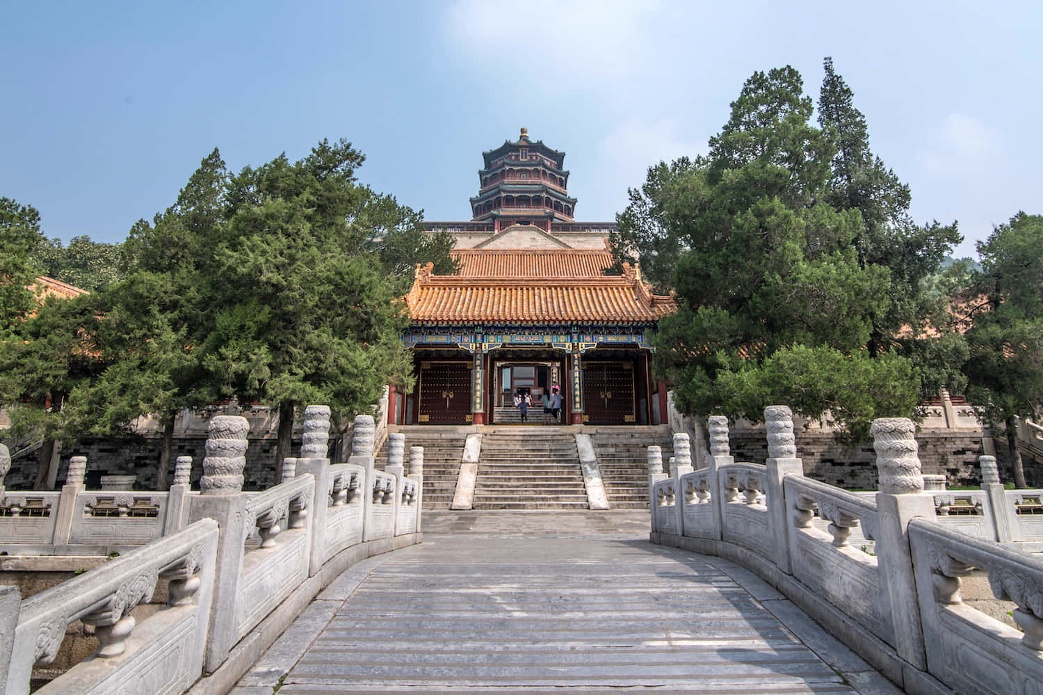 通往故宮的階梯 壁紙 — 一座宏偉的傳統中國寺廟，擁有橙色瓦頂和石橋，在清澈的藍天下。