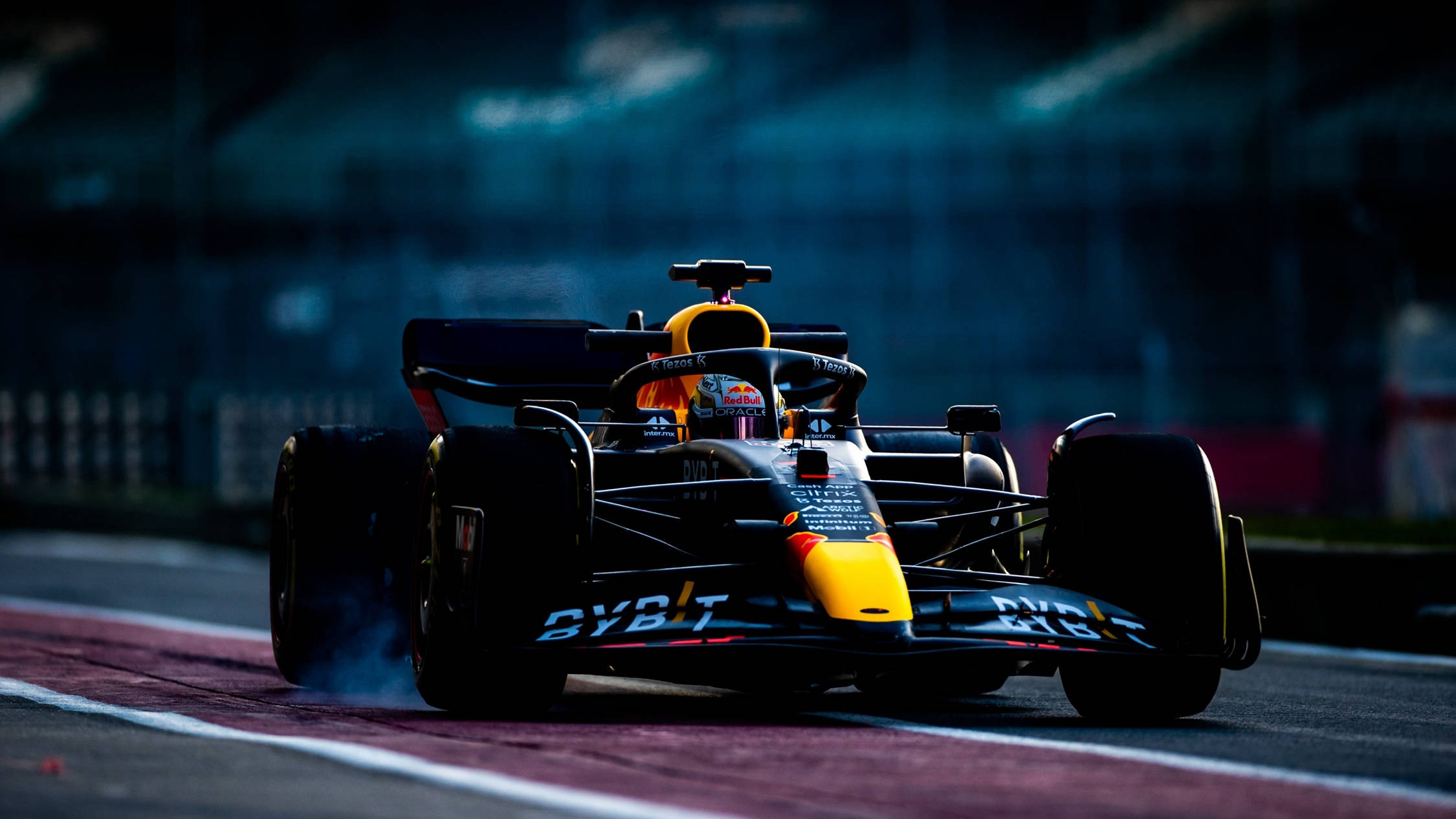 速度決勝一級方程式賽車 壁紙 — 一輛紅牛一級方程式賽車在夜間光線昏暗的賽道上飄移，輪胎冒出煙霧。