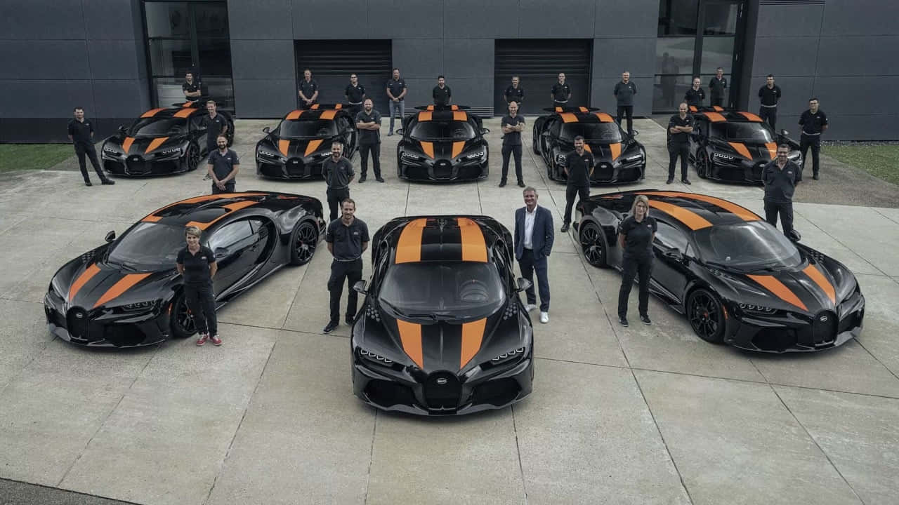 Bugatti員工團隊在現代建築前與黑色和橙色超跑合影。