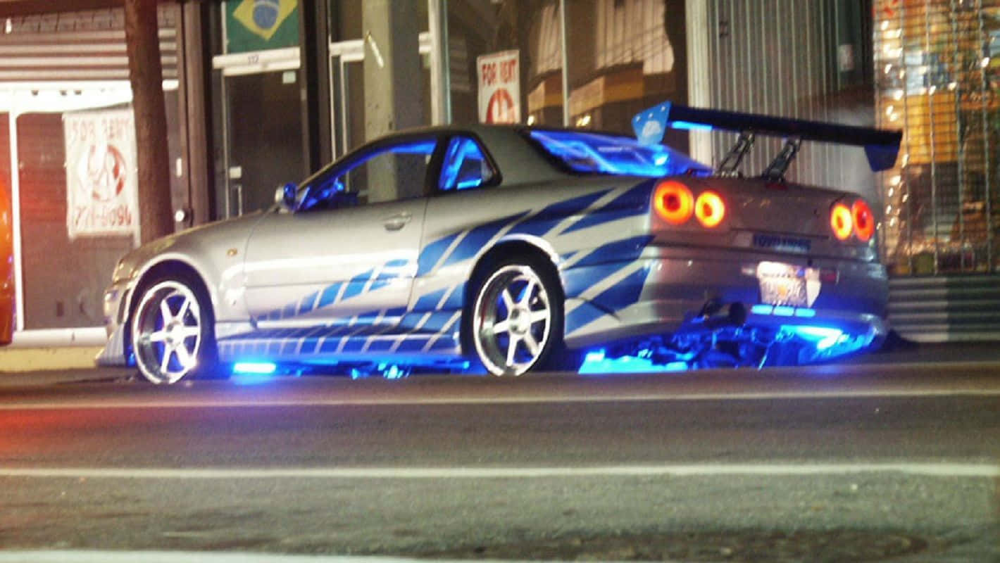 定制銀色日產Skyline GT-R，帶藍色燈光，夜晚停在城市街道上。