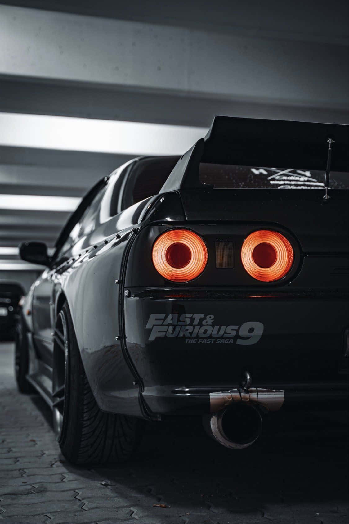 黑色日產Skyline R34，在地下車庫中帶有發光的橙色尾燈。