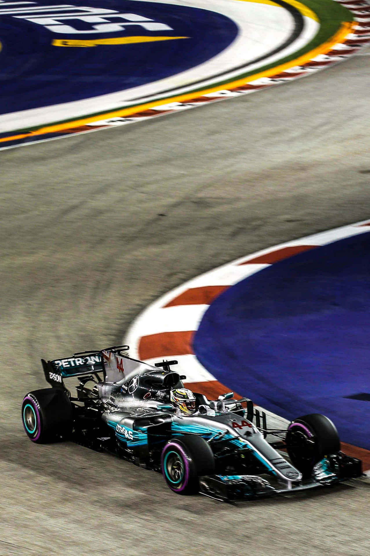F1賽車在明亮的燈光下於夜間賽道彎道疾馳。
