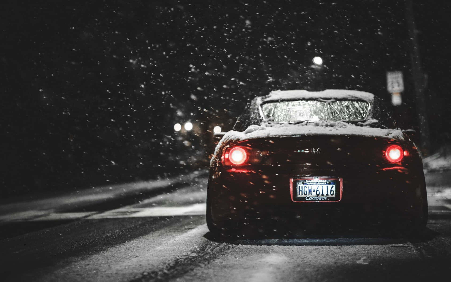 黑色跑車配紅色尾燈在夜間雪地行駛。