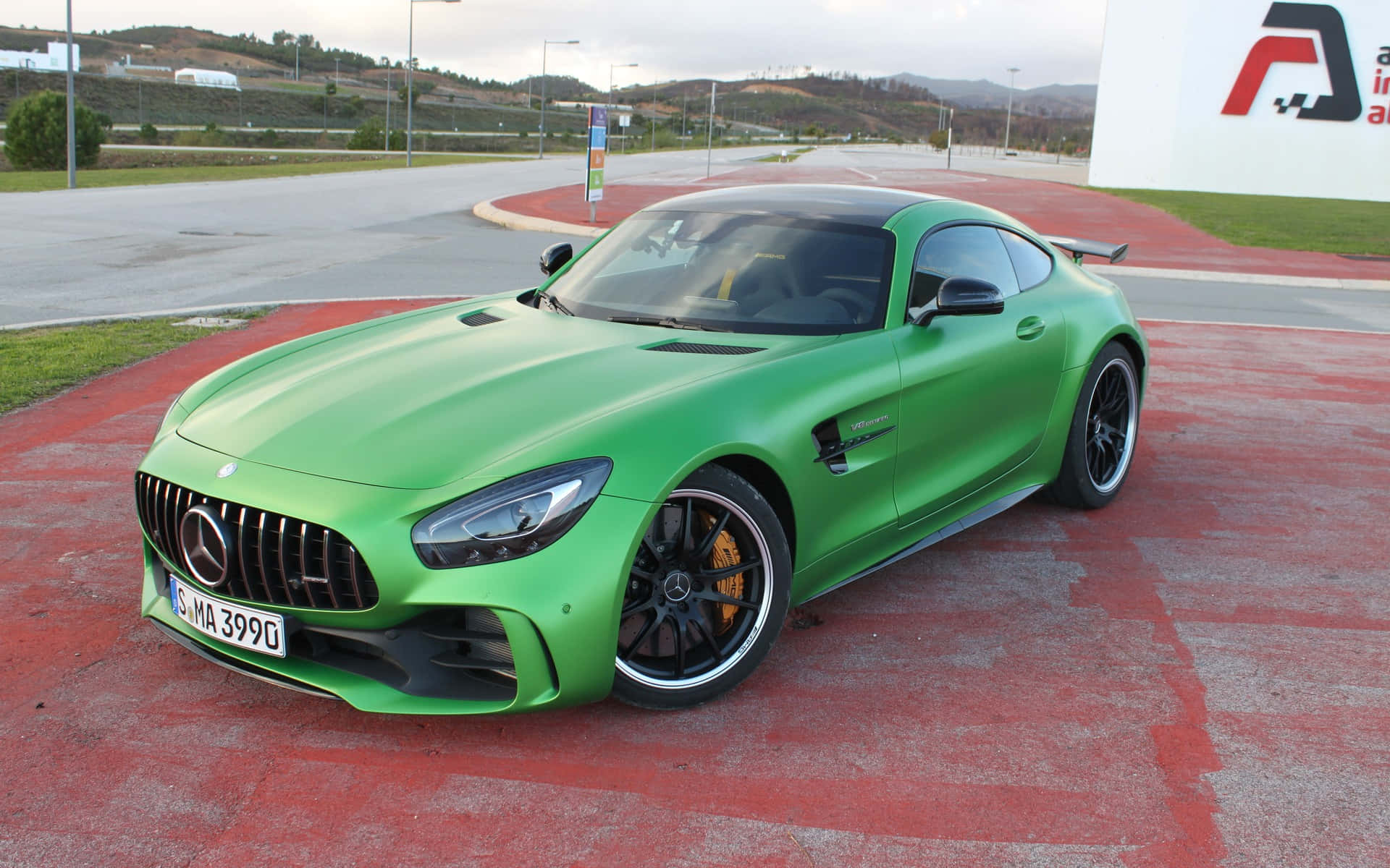 綠色 Mercedes-AMG GT R 跑車停泊在紅色路面上，附近有山丘。