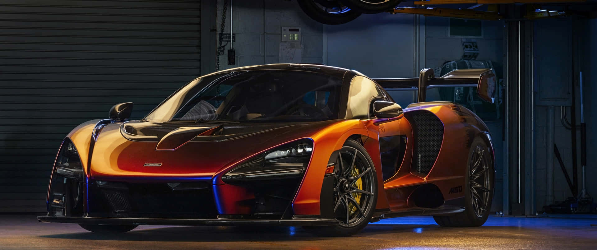 橙色McLaren Senna跑車在帶藍色燈光的車庫中。