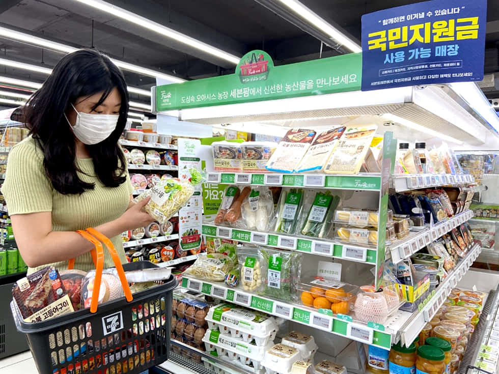 戴口罩女性在韓國超市通道選購蔬菜。