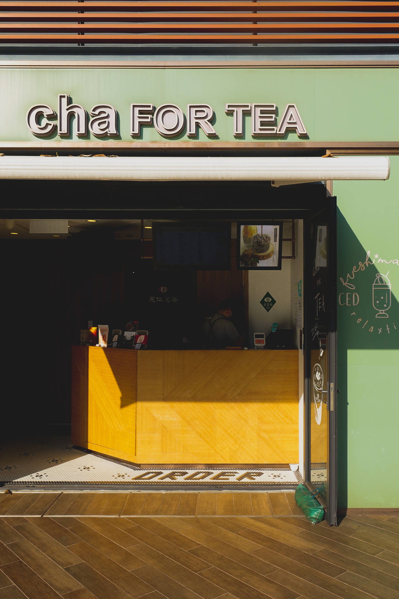 現代茶店，綠色牆壁和木製櫃檯沐浴在陽光中。