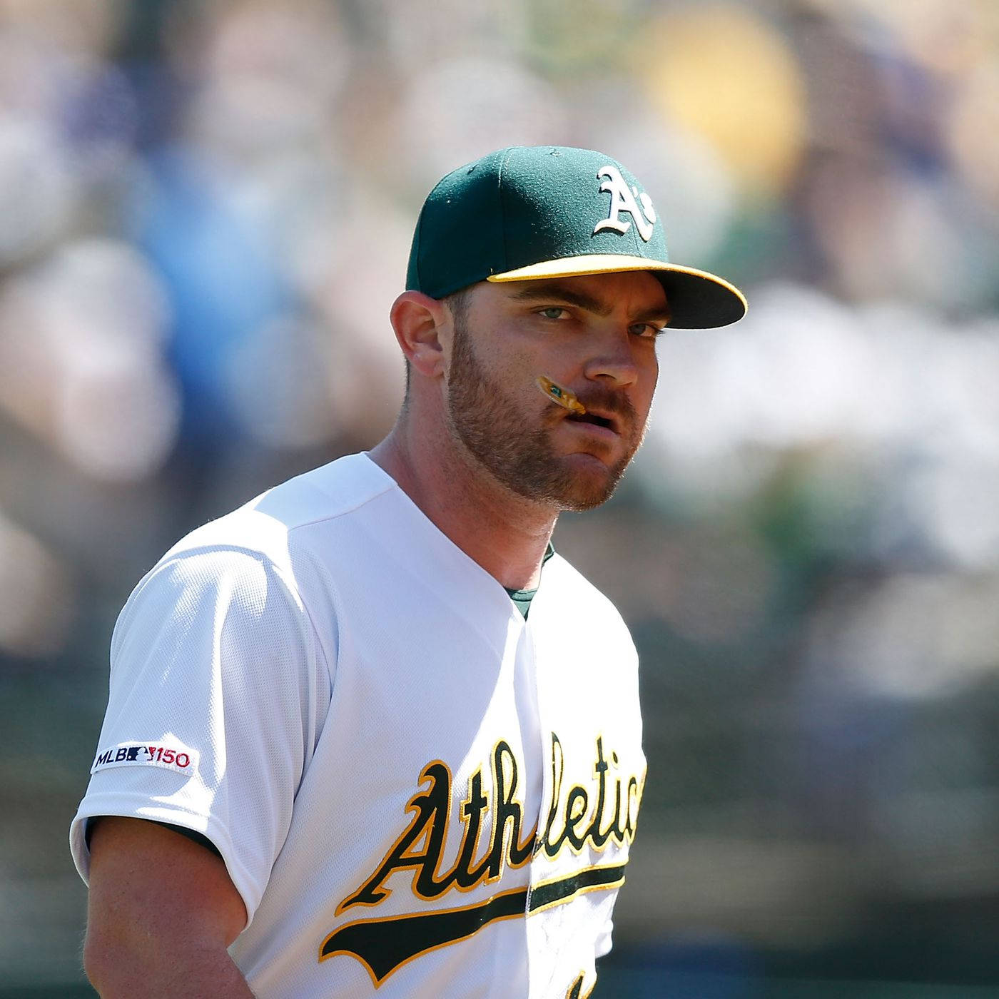 連恩·亨德里克斯嚴肅表情 壁紙 — 身穿奧克蘭運動家隊球衣的棒球選手，在日間比賽中嘴裡含著一根草莖。