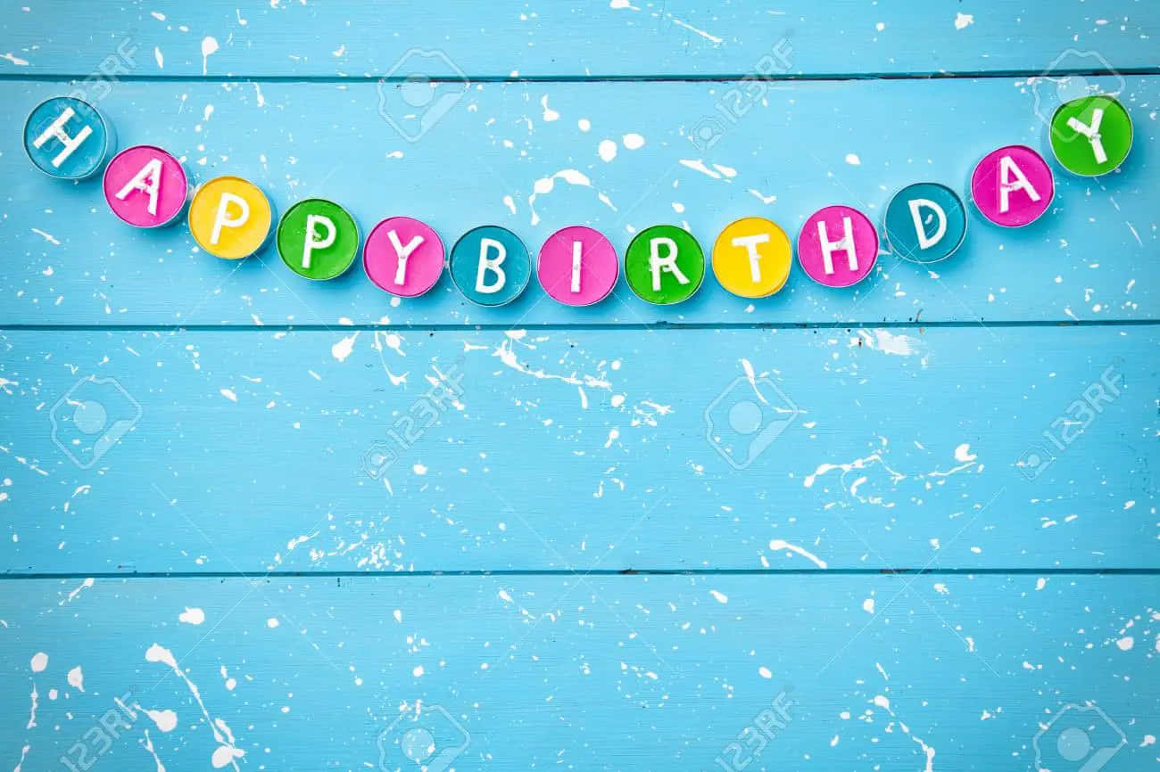 Happy Birthday 字母在彩色圓圈中，背景為帶有油漆飛濺的藍色木質表面。