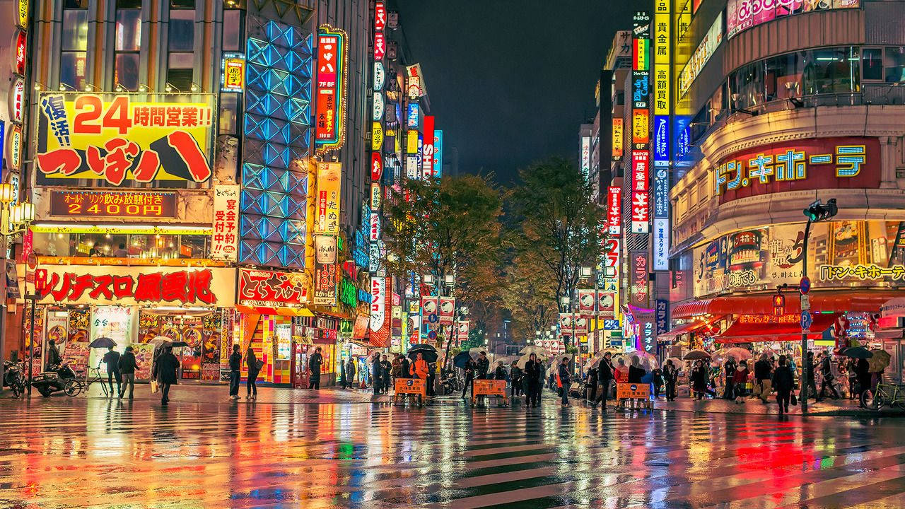 下雨的東京夜晚街道，有發光的霓虹燈牌和行人。