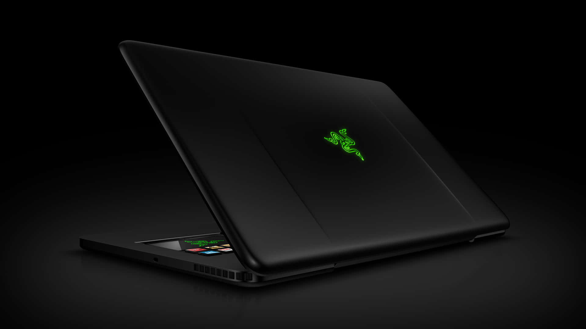 黑色 Razer 遊戲筆記型電腦，帶有發光的綠色標誌，在黑暗表面上打開。