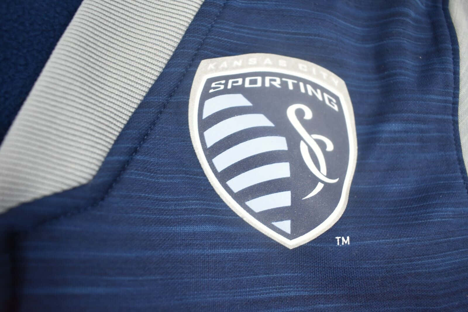 運動家堪薩斯城隊標誌印於藍灰球衣 壁紙 — Sporting Kansas City 藍灰色足球球衣特寫，隊徽清晰可見。