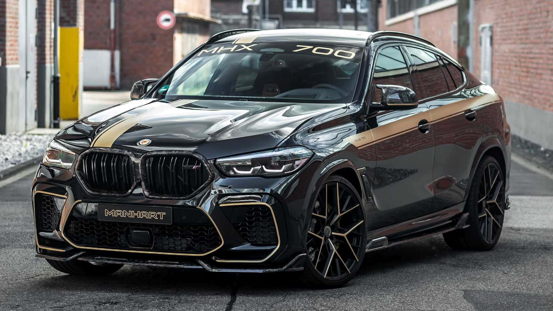 運動與奢華兼具的 BMW X6 M 壁紙 — 一輛光澤黑色Manhart改裝BMW X6 M，帶金色點綴，停在磚砌城市街道上。