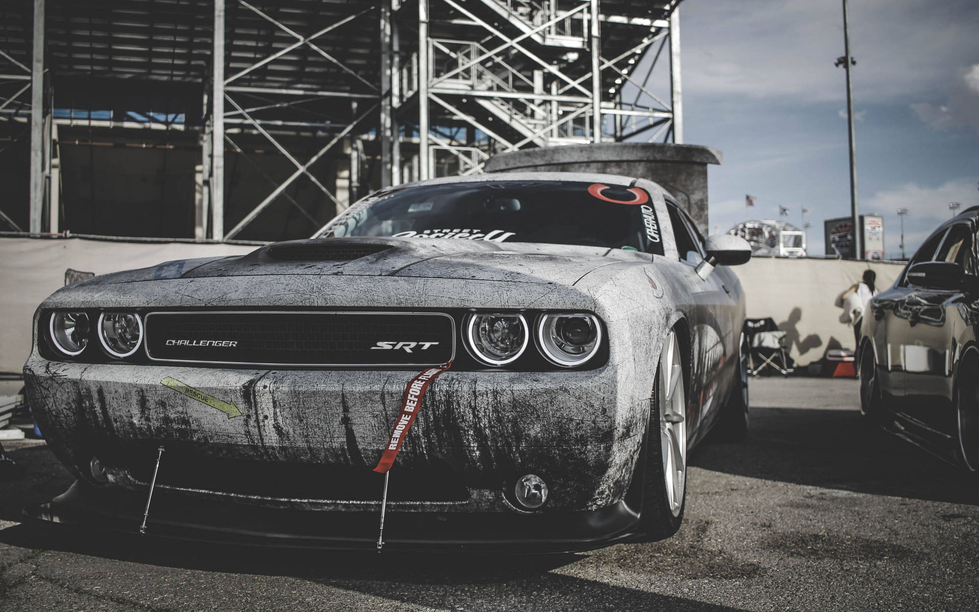 一架佈滿灰塵的灰色 Dodge Challenger SRT 停泊在賽車場上。 — Dodge challenger GIF 壁紙