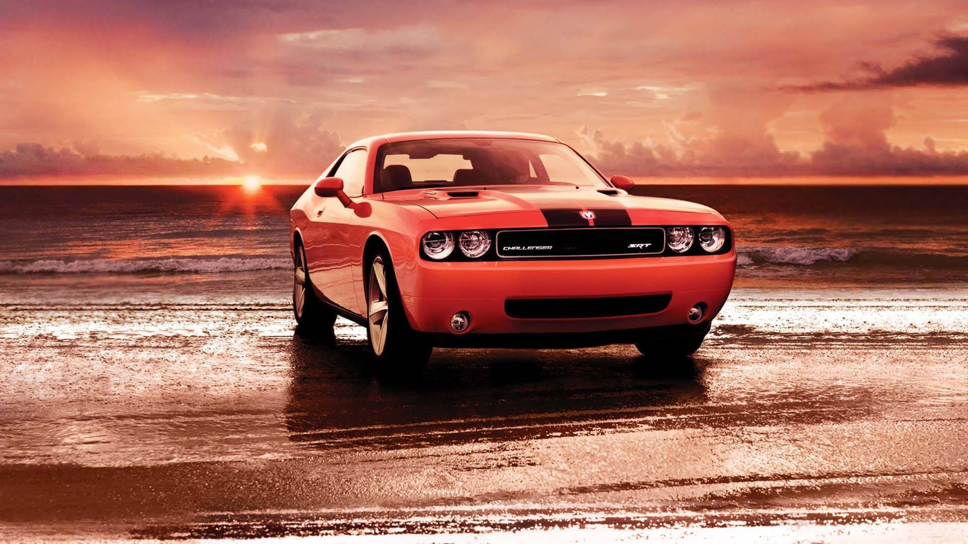 橙色 Dodge Challenger SRT 在日落時分停在濕海灘上，海浪拍打