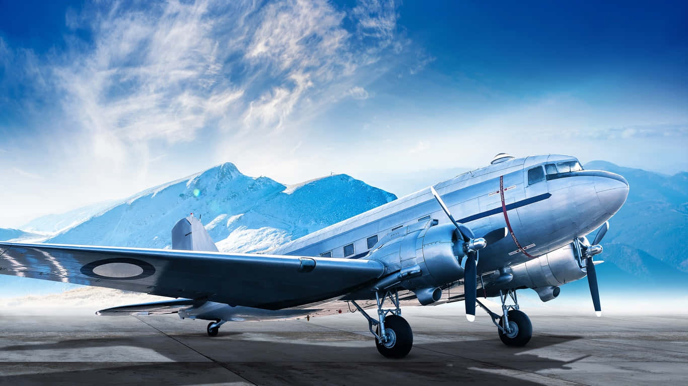 道格拉斯 DC-3 停泊於雪山旁跑道的巨型客機背景（1366x768） 壁紙 — 一架復古銀色螺旋槳飛機停在跑道上，背景是白雪覆蓋的山脈和明亮的藍天。