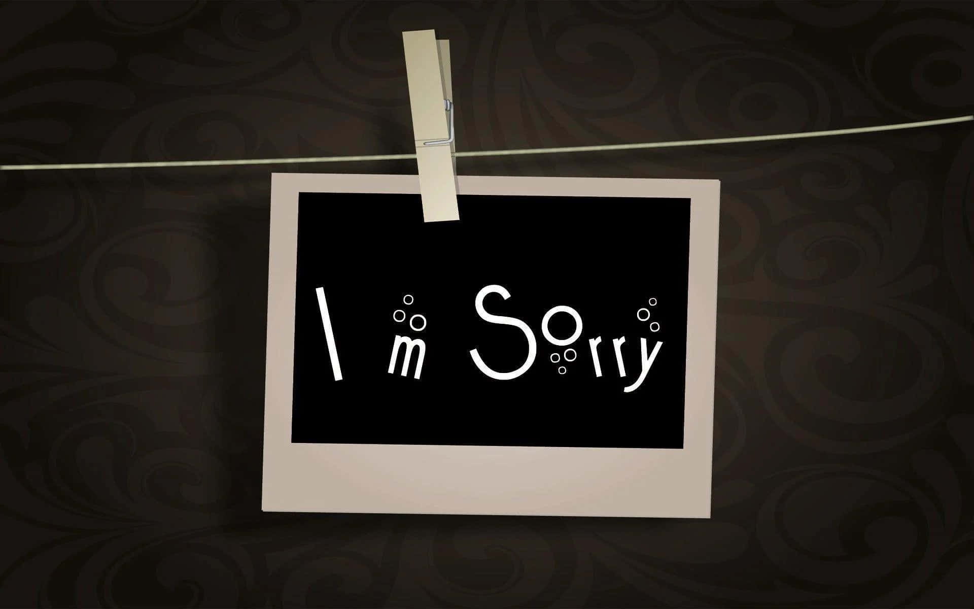 一張帶有 'I'm Sorry' 文字的照片，用衣夾掛在電線上。