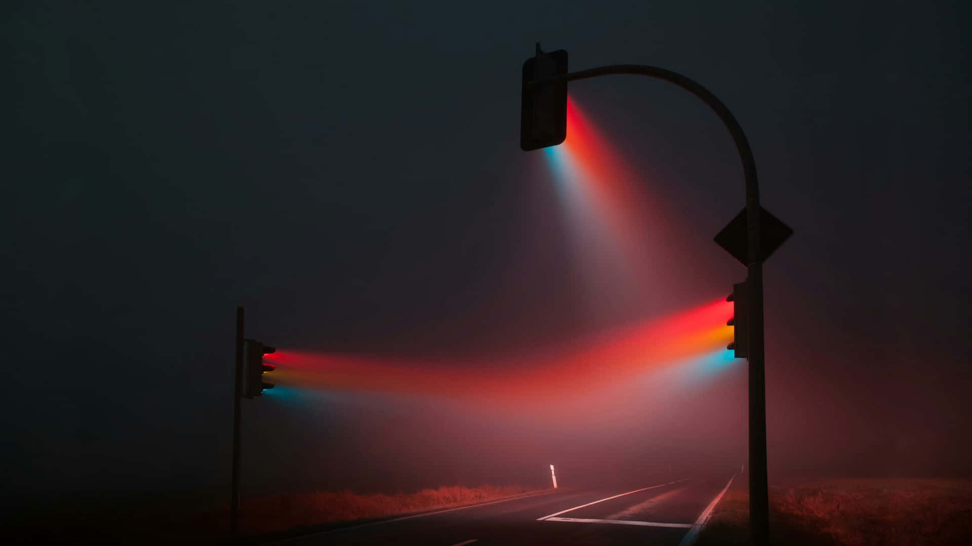 交通燈在霧氣籠罩的夜晚道路上發出紅光和藍光。