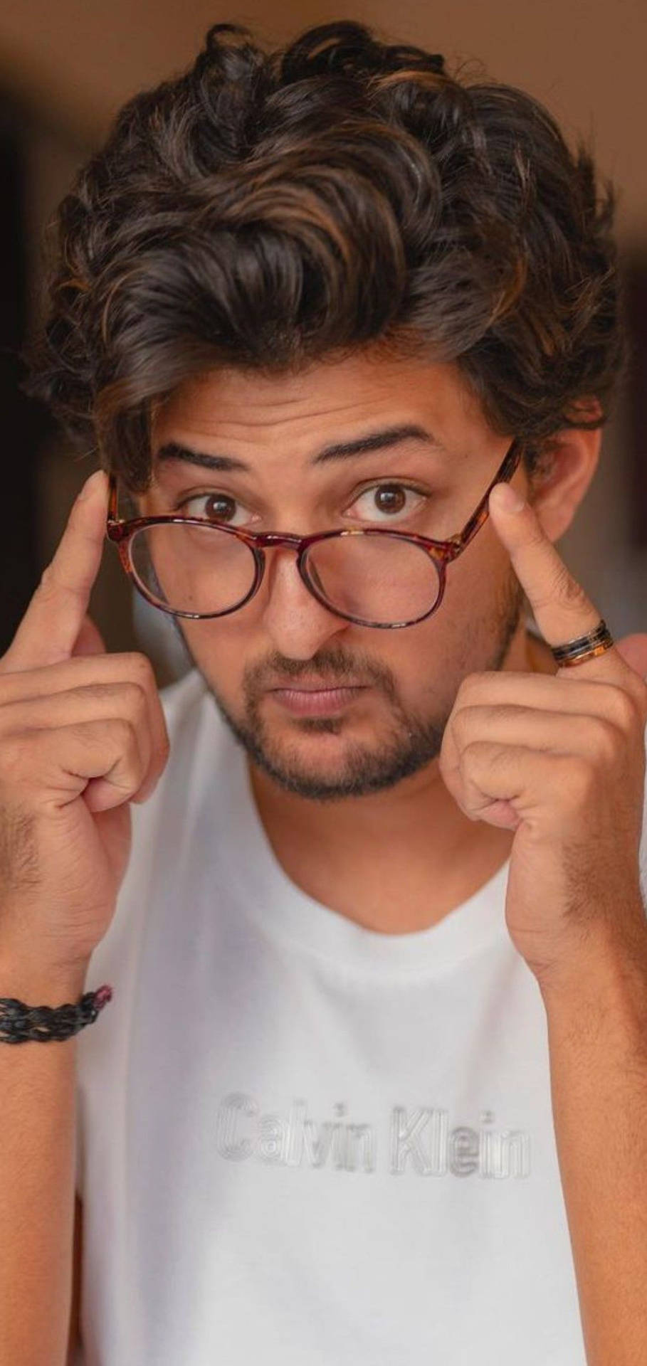 戴眼鏡的年輕男子以俏皮的表情指著太陽穴。